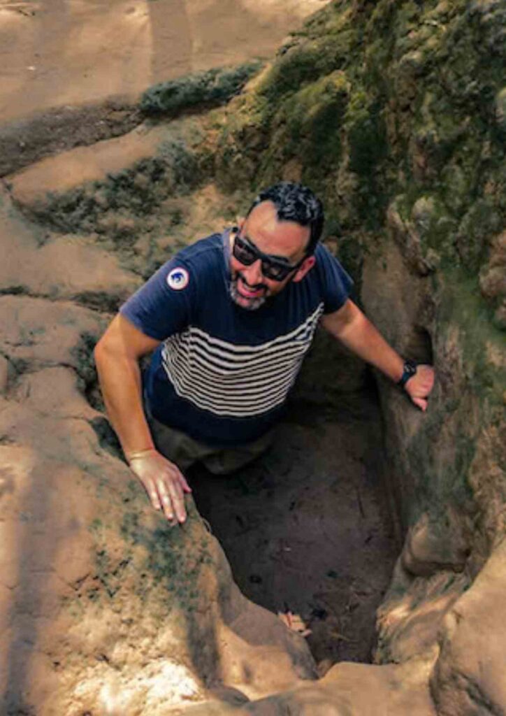 A male tourist coming out of an enlarged bunker entrance during a Cu Chi tunnel small group tour