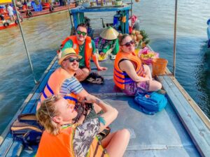 Travelers enjoying an authentic Mekong Delta floating market boat cruise during a day trip from Ho Chi Minh City.
