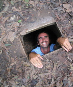 A happy male tourist look up from a hidden underground entrance on a Cu Chi and Ho Chi Minh city tour in one day