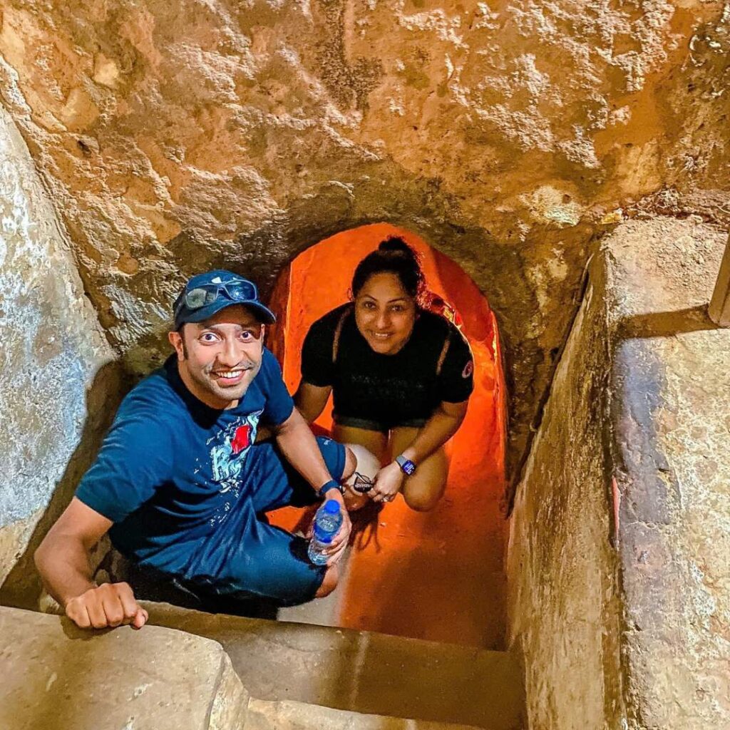 Happy travelers emerging from a narrow, illuminated underground passage during a guided Cu Chi Tunnels tour in Saigon, Vietnam with Saigon Adventure.