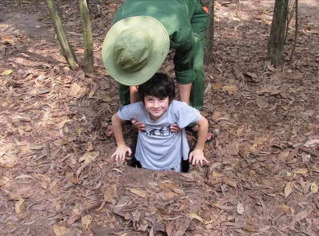 Kid enjoy our tour at the hidden trapdoor at Cu Chi Tunnels tour with Saigon Adventure
