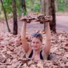Authentic Cu Chi Tunnels Experience with tourist demonstrating a hidden underground entrance