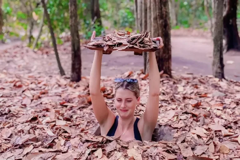 Authentic Cu Chi Tunnels Experience with tourist demonstrating a hidden underground entrance