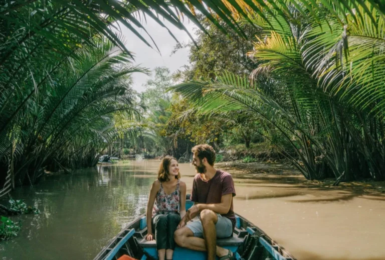 Tourists on a traditional boat ride surrounded by lush greenery during a Mekong Delta tour.