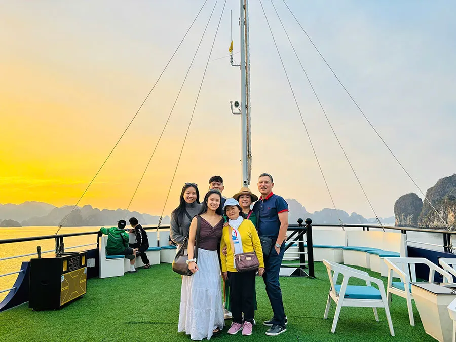 Halong Sonata Cruise with transfer and lunch, travelers enjoying luxury cruise, stunning sunset and iconic limestone islands in Halong Bay, Vietnam.