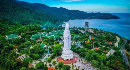 Aerial view of the Linh Ung Pagoda complex and the giant Lady Buddha statue on the lush Son Tra Peninsula overlooking Da Nang Bay.