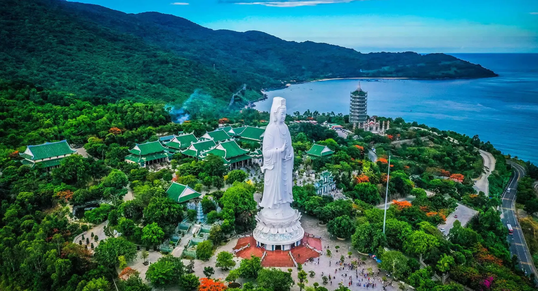 Aerial view of the Linh Ung Pagoda complex and the giant Lady Buddha statue on the lush Son Tra Peninsula overlooking Da Nang Bay.
