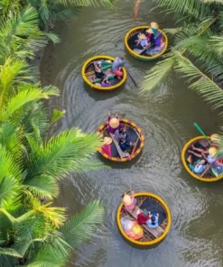 Aerial view of colorful Vietnamese basket boats navigating through the lush green palm canals of Bay Mau Coconut Forest in Hoi An.