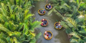 Aerial view of colorful Vietnamese basket boats navigating through the lush green palm canals of Bay Mau Coconut Forest in Hoi An.