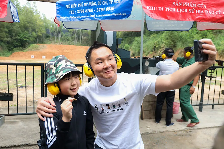 Excited Japanese tourist and his son posing for a photo with a real M16 bullet at Cu Chi Tunnels shooting range.