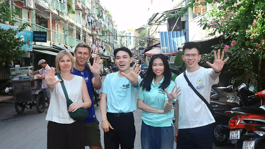 International visitors exploring a hidden alley with local guides during a Ho Chi Minh City walking tour in District 1.