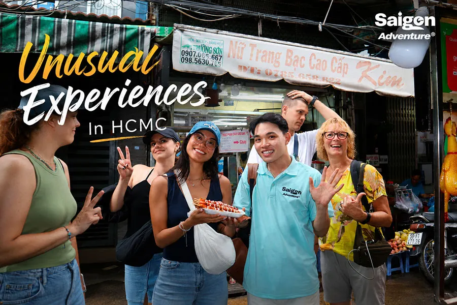 Unusual Experiences in HCMC with international tourists enjoying authentic Vietnamese street food alongside a local guide in a lively Ho Chi Minh City market.