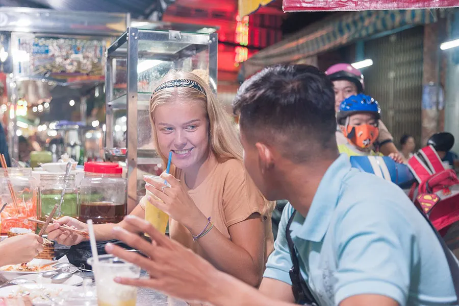 Why Are Vietnamese Morning Markets So Busy? 7 Tourists eating authentic Vietnamese breakfast at a busy local market in Saigon
