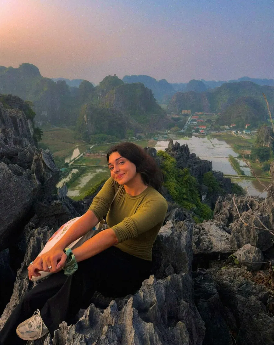Hoa Lu Ancient Capital Guide: History, Temples and Travel Tips 3 Traveler resting on limestone rocks overlooking Tam Coc countryside