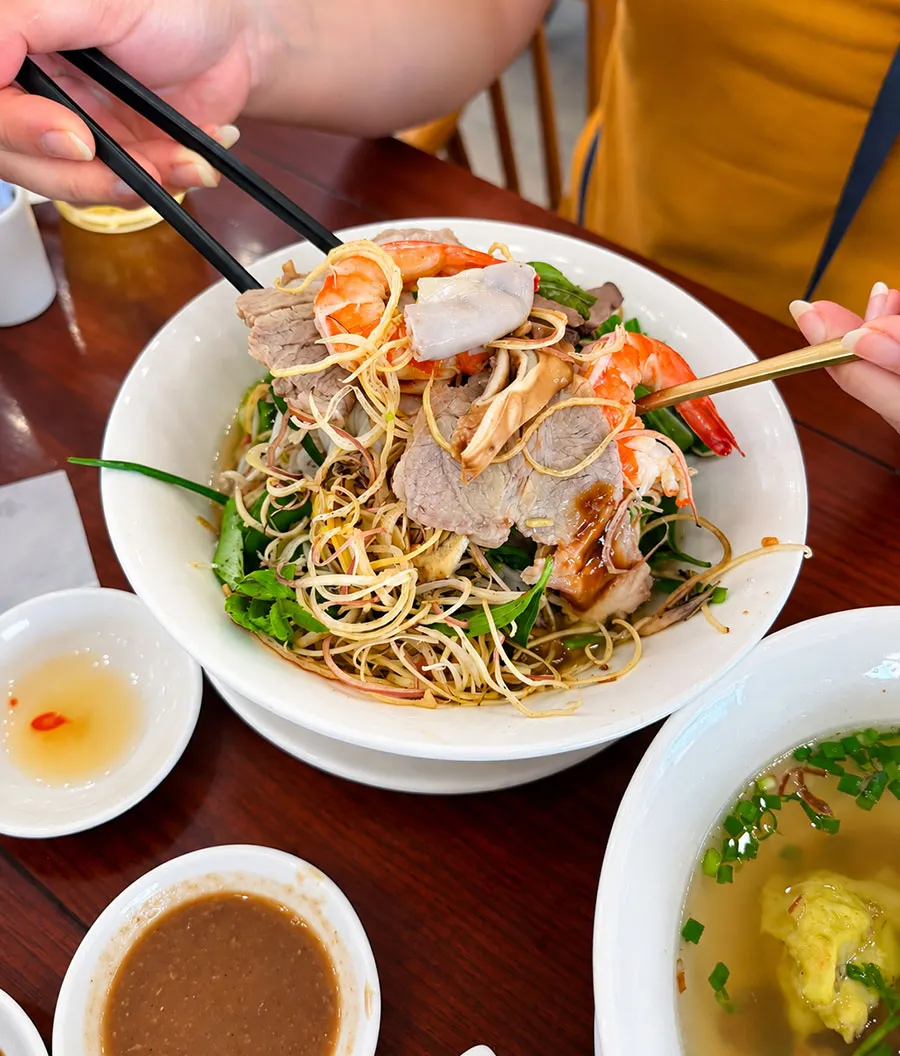 Hu Tieu Kho vs Hu Tieu Nuoc: Which Should You Try in Saigon? 1 Dry hu tieu in Saigon served with seasoned noodles and broth on the side