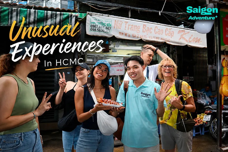 Unusual Experiences in HCMC with international tourists enjoying authentic Vietnamese street food alongside a local guide in a lively Ho Chi Minh City market.
