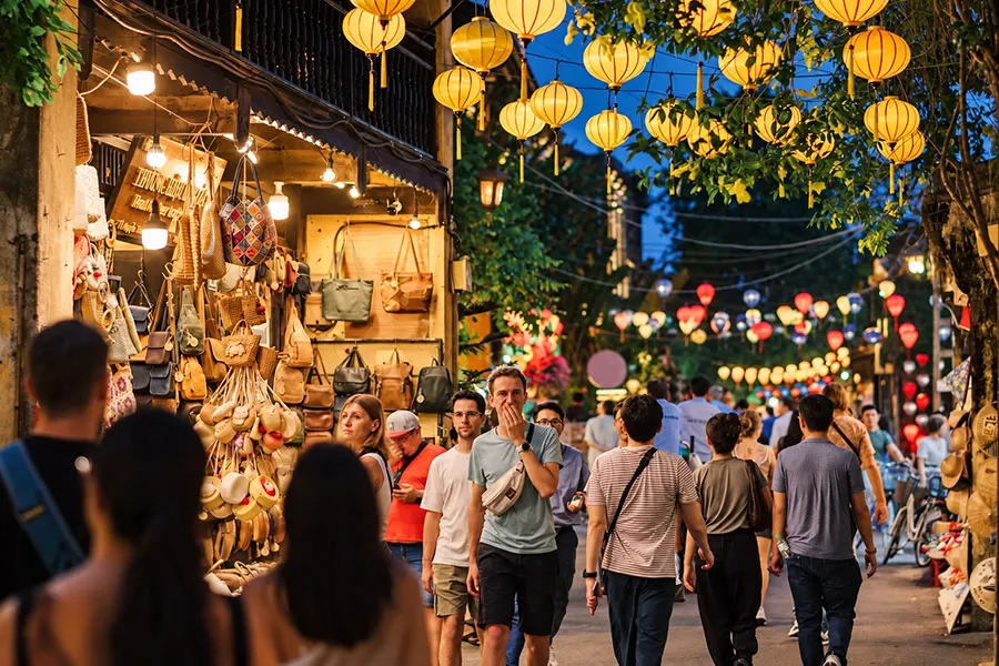 Hoi An Night Market Food Guide: What to Try Beyond the Souvenir Stalls 2 Travelers browsing lanterns and local souvenirs at Hoi An Night Market