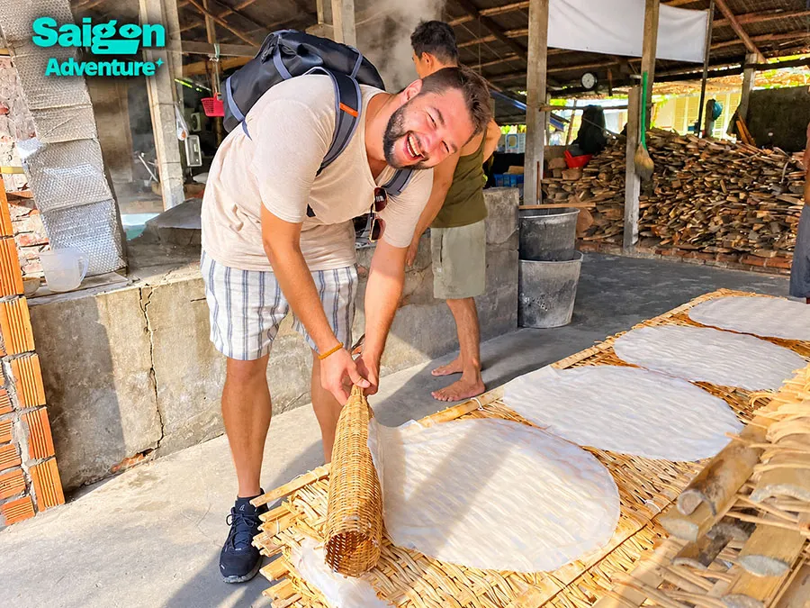 Vinh Long Mekong Delta: Homestays, Cycling and Orchards 7 Happy traveler exploring a traditional rice paper workshop in the Mekong Delta